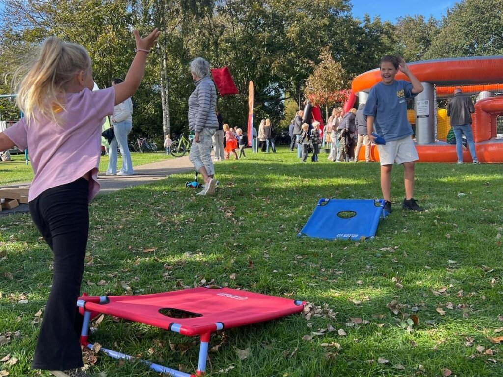 Kinderen spelen een werpspel op het gras tijdens een buitenspeeldag georganiseerd door Move For Fun
