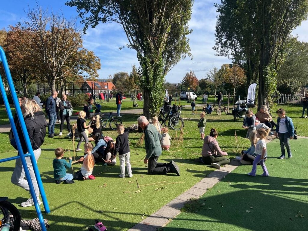 Kinderen spelen samen met hulp van ouders in een park tijdens de buitenspeeldag georganiseerd door Move For Fun