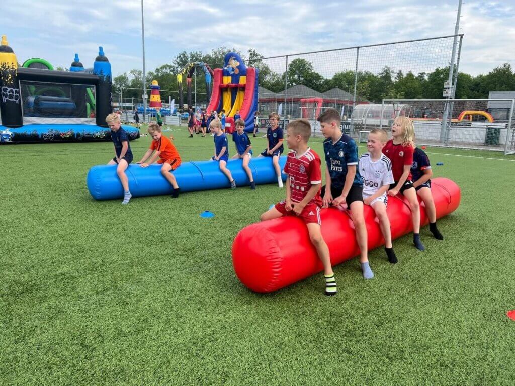 Kinderen genieten van een actief schoolreisje op een sportveld met opblaasbare spellen en springkussens van Move For Fun.