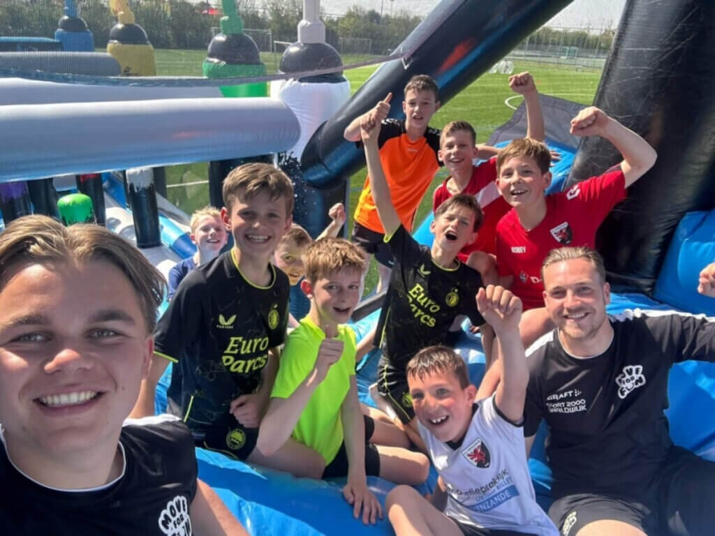 Kinderen genieten van een sportief schoolreisje op een opblaasbare stormbaan tijdens een Move for Fun evenement.