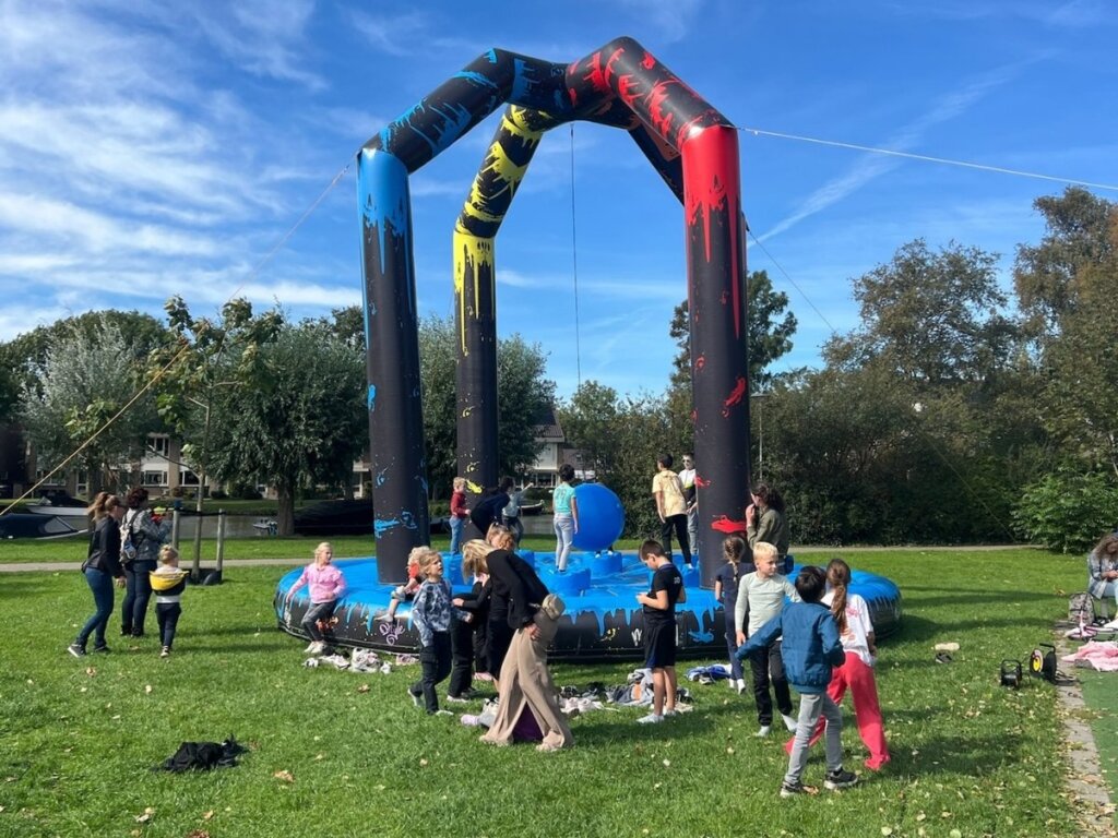 Groep kinderen speelt op een grote opblaasbare spelactiviteit tijdens de buitenspeeldag van Move For Fun