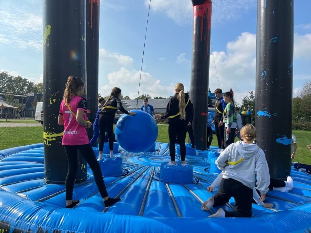 Groep jongeren speelt samen op een opblaasbare activiteit tijdens een introductiedag georganiseerd door Move For Fun.