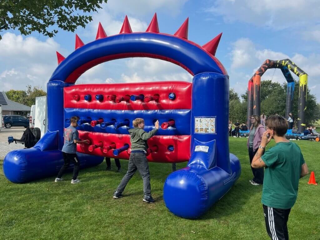 Kinderen spelen een actief opblaasbaar klim- en duwspel tijdens de zeskamp van Move For Fun op een zonnige buitendag.