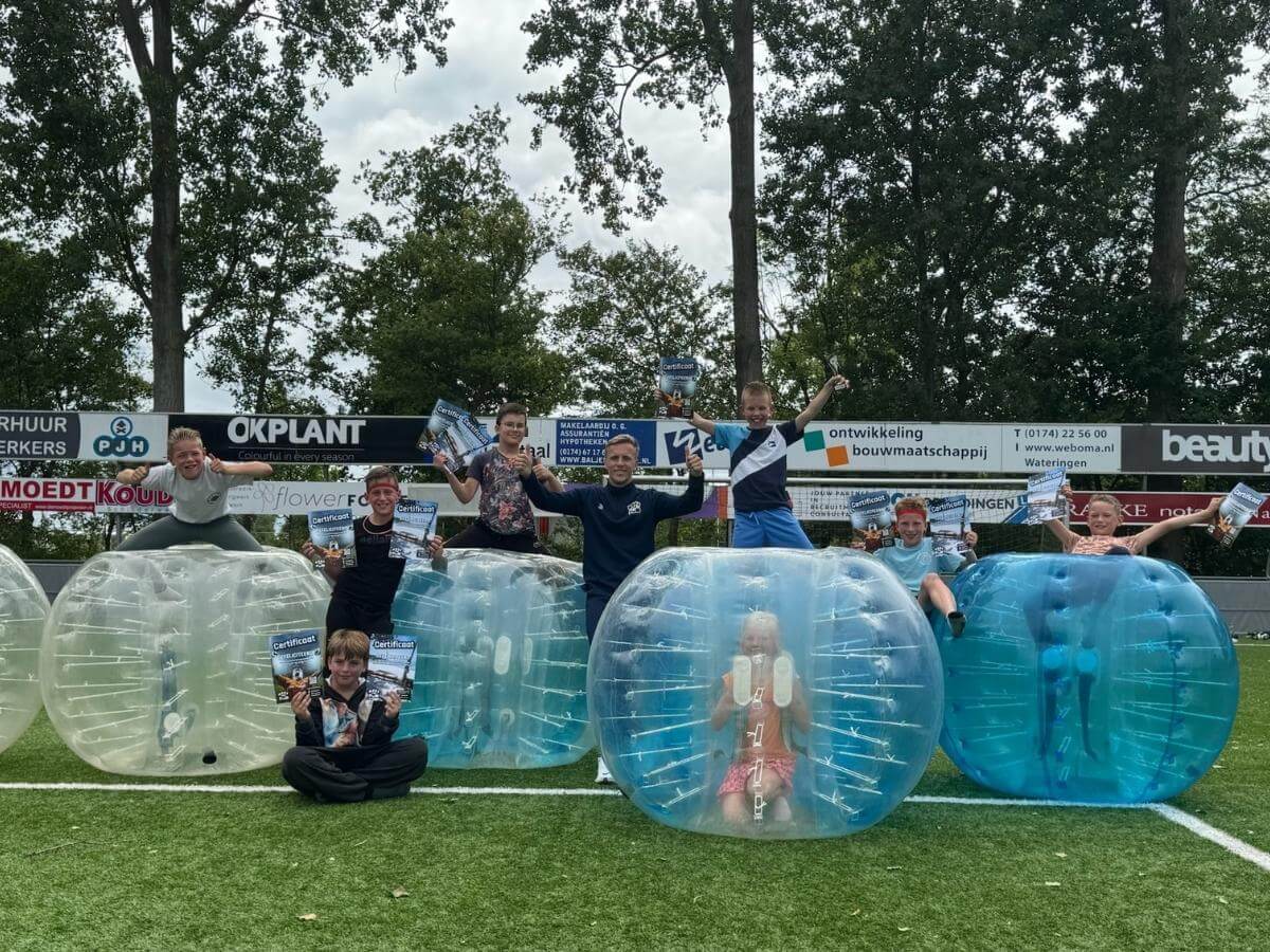Kinderen poseren op bubbelballen tijdens bubbel voetbal feestje buiten.
