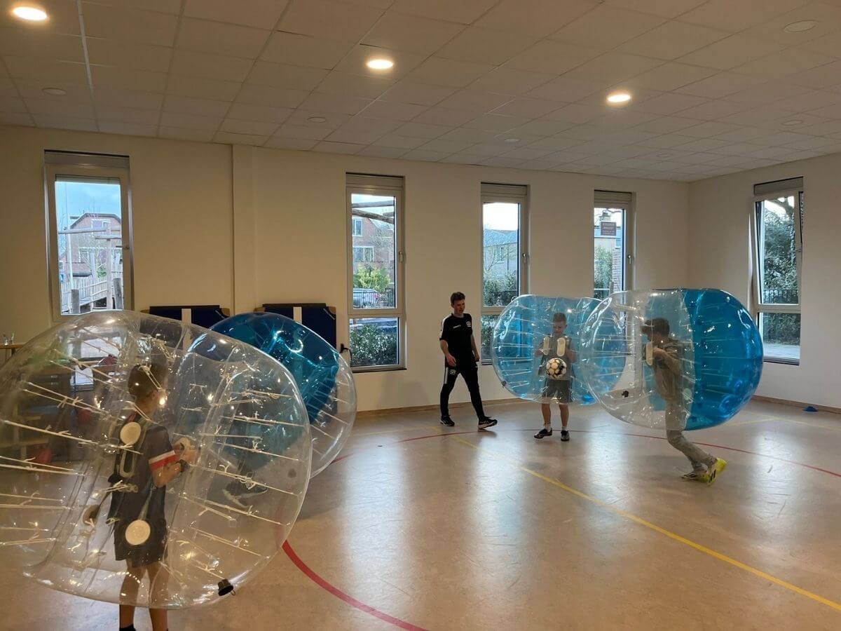 Actie tijdens Bubbel Voetbal Kinderfeestje Kinderen rennen en botsen in bubbelballen tijdens Bubbelvoetbal kinderfeestje.