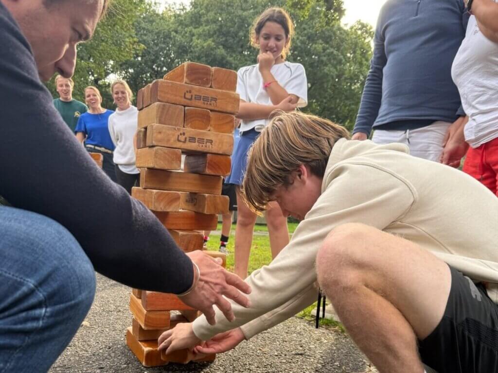 Volwassenen en kinderen spelen een actief spel met tennisballen tijdens Burendag in de wijk.