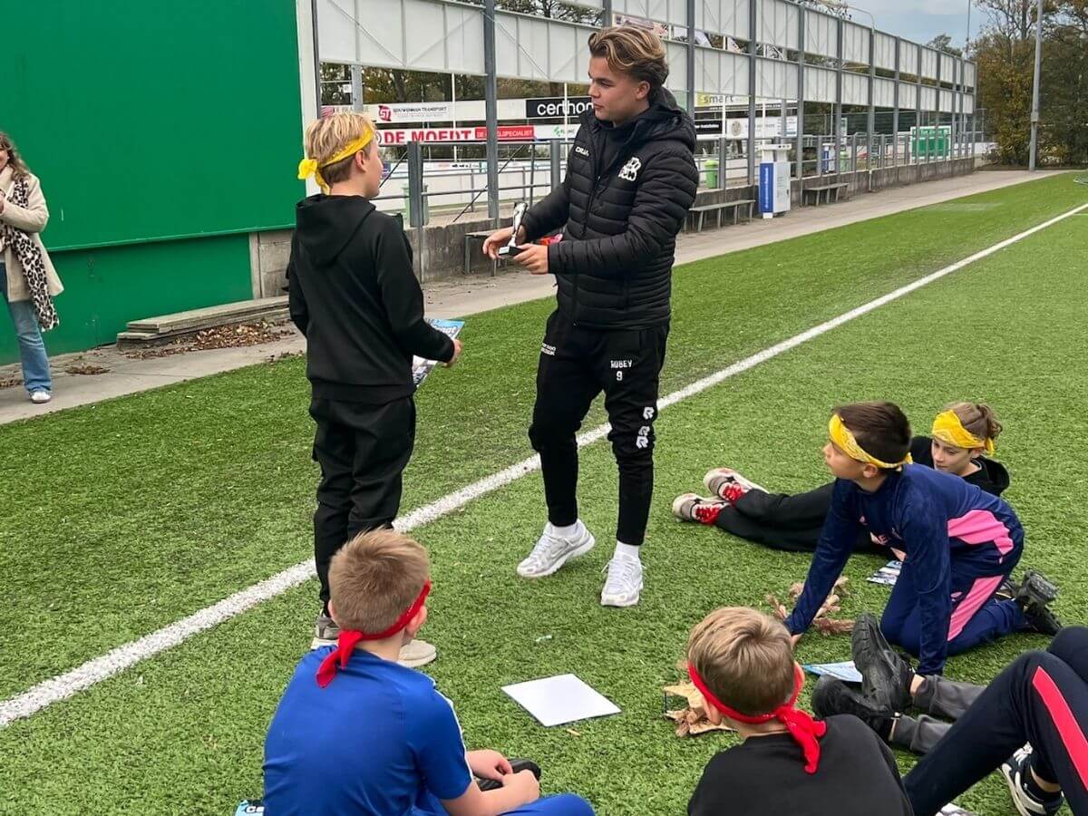 Certificaatuitreiking Expeditie Robinson kinderfeestje Instructeur reikt certificaat uit aan kind tijdens Expeditie Robinson kinderfeestje