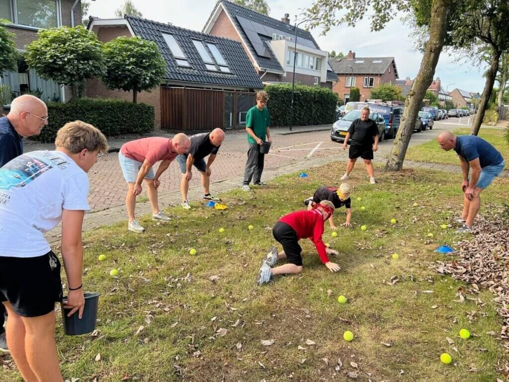 Families doen mee aan een sportieve buitenactiviteit met tennisballen tijdens een familiedag van Move For Fun.