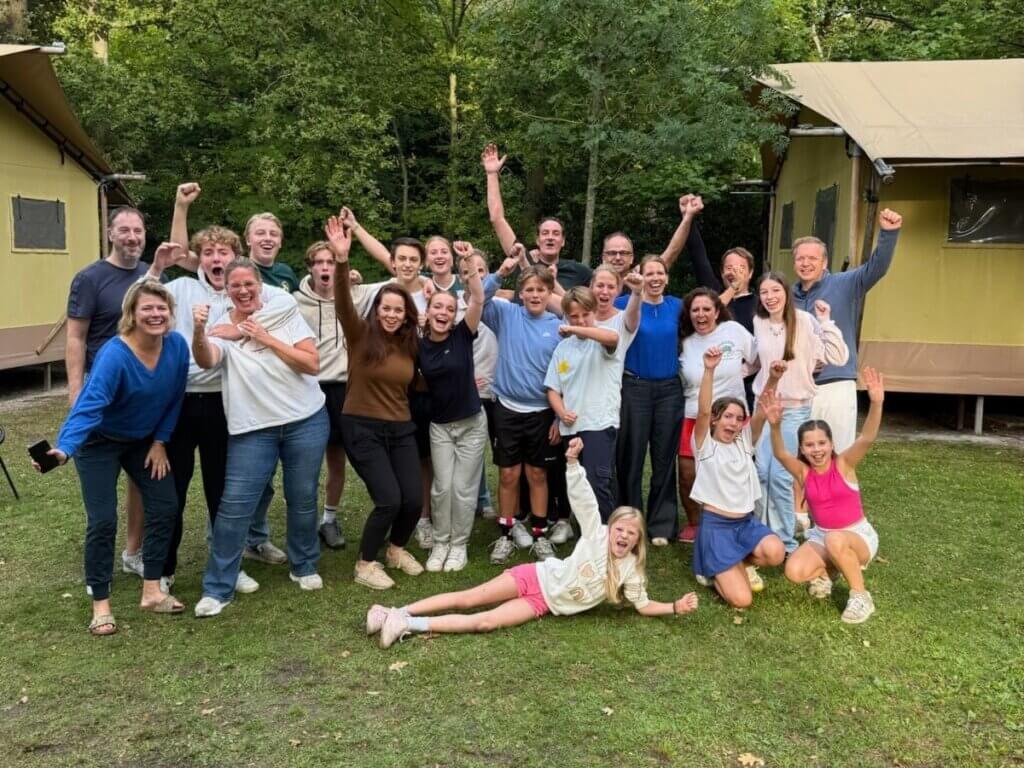 Een groep familieleden juicht samen tijdens de familiedag, zichtbaar vrolijk en verbonden.