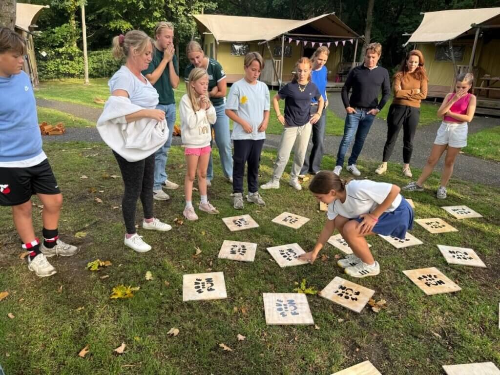 Een groep mensen speelt reuze memory op de familiedag, geconcentreerd en serieus kijkend naar de kaarten.