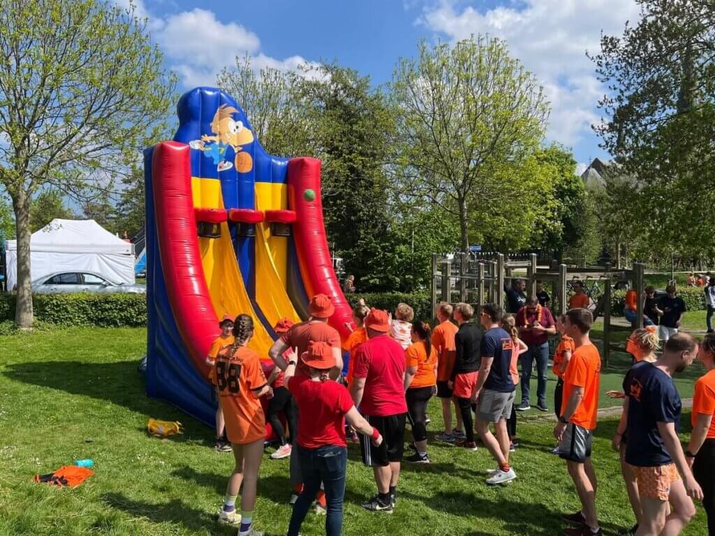 Spellen spelen op koningsdag met een groep deelnemers in oranje kleding.