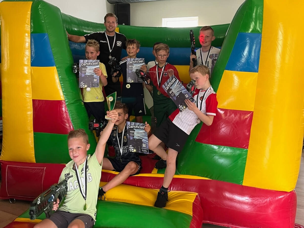 Lasergame Kinderfeestje – Groepsfoto op Springkussen Kinderen met certificaten op een springkussen tijdens een lasergame kinderfeestje