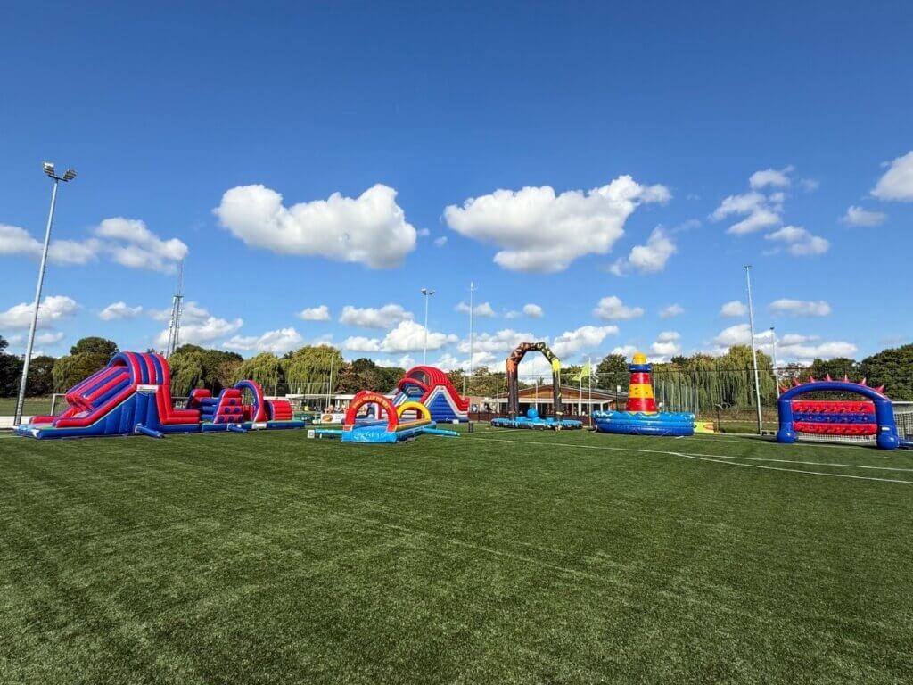 Grote opblaasattracties op een voetbalveld tijdens een seizoensafsluiting, georganiseerd door Move For Fun.