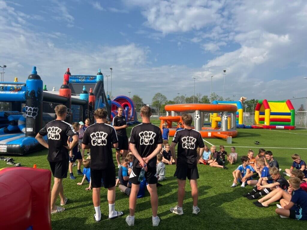 Groep kinderen poseert met Move For Fun-begeleiders tijdens een actieve seizoensafsluiting vol sport en plezier.