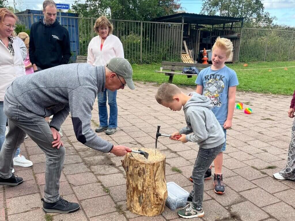 Een kind speelt een spelletje spijkerslaan tegen een volwassen man.