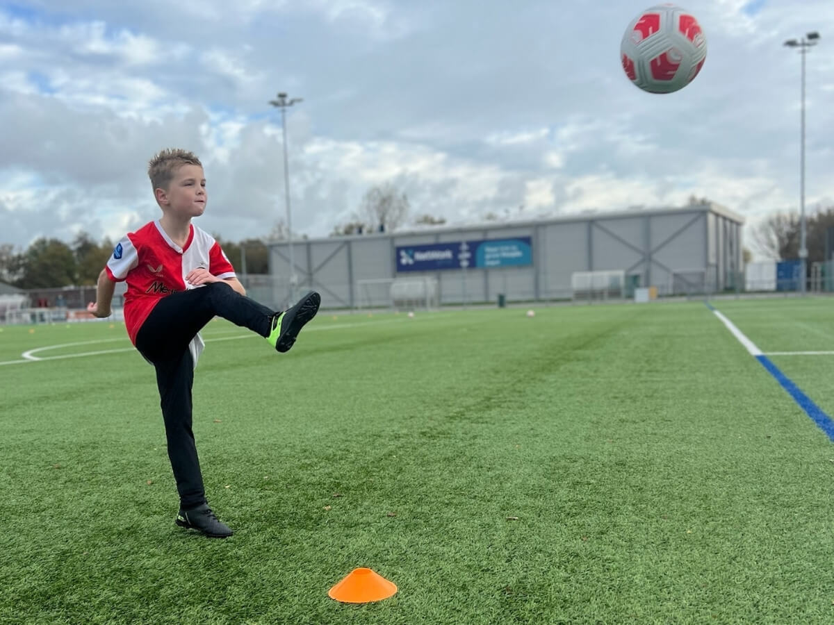 Voetbal kinderfeestje – Kind trapt de bal tijdens een schotoefening Jongen trapt een voetbal tijdens een oefening op het veld bij het voetbal kinderfeestje van Move For Fun.