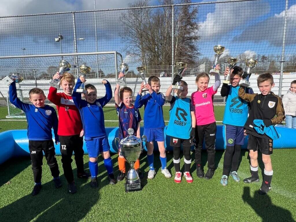 Kinderen vieren hun overwinning met bekers tijdens de seizoensafsluiting van Move For Fun.