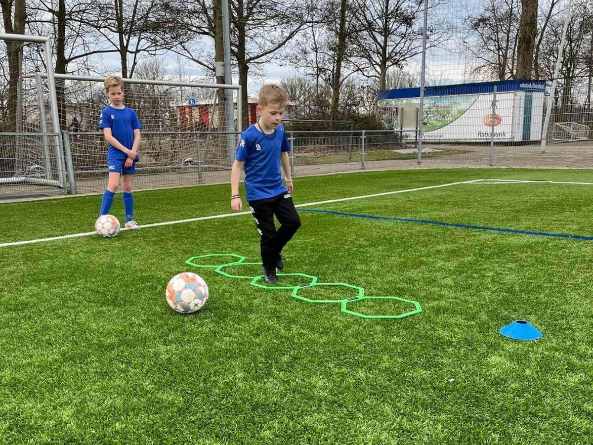 FIFA Voetbalfeestje – Coördinatie Skill Game Kind doet coördinatie-oefening over ringen tijdens het voetbal FIFA kinderfeestje.