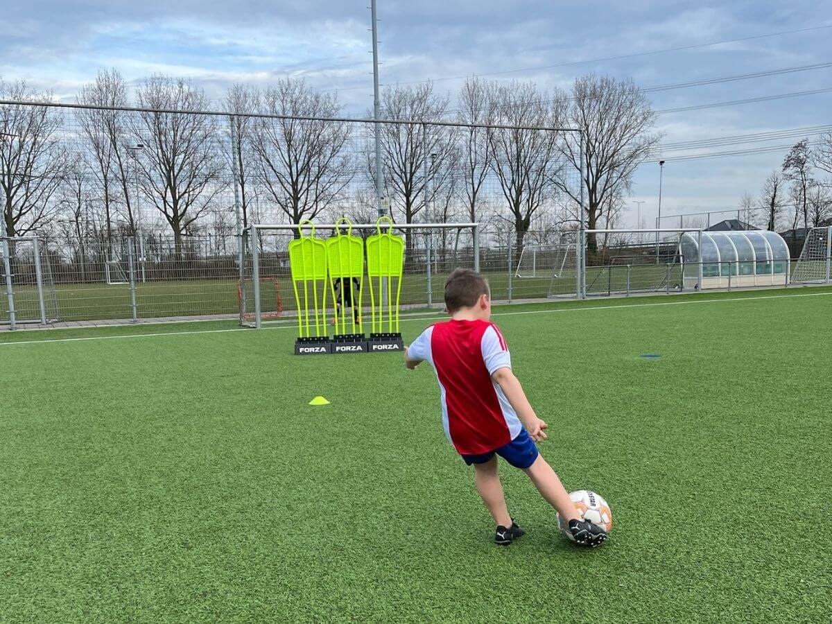 FIFA Kinderfeestje – Vrije Trap Oefening Kind schiet een vrije trap over de poppenwand tijdens het FIFA voetbal kinderfeestje.