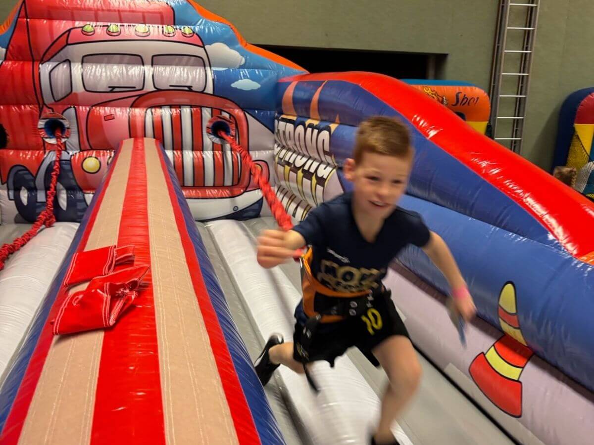Bungee run voor kinderen tijdens sport- en speldag Kind rent over de bungee run tijdens een sport- en speldag met opblaasbare attracties van Move For Fun