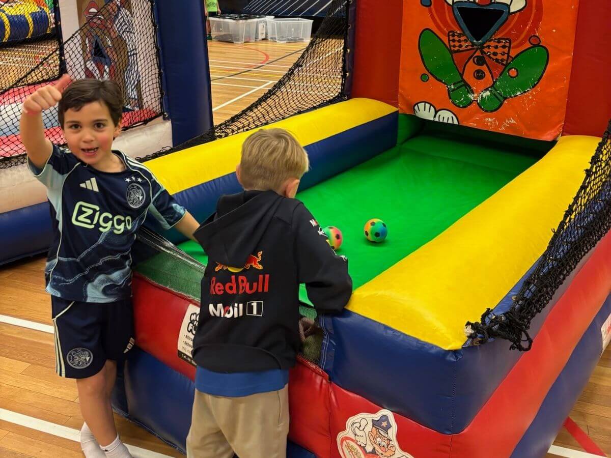 Opblaasbaar spel voor kinderen tijdens sport- en speldag Kinderen spelen een opblaasbaar spel tijdens een sport- en speldag van Move For Fun in de sporthal