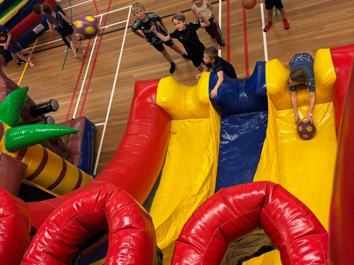 Sport- en speldag met opblaasbare spellen voor kinderen Kinderen spelen sport- en spelactiviteiten met opblaasbare spellen tijdens een sport- en speldag in sporthal De Pijl