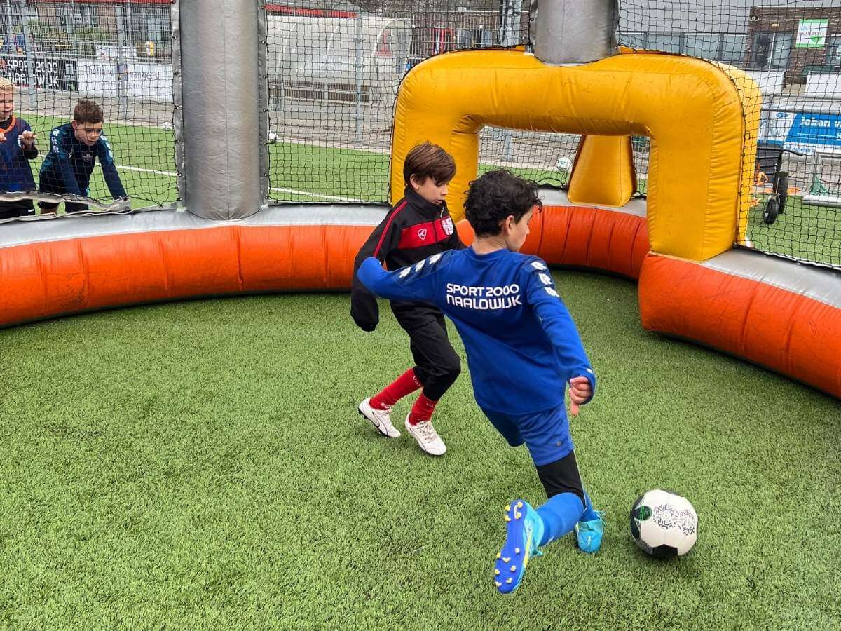 Kinderen spelen een 1-tegen-1 voetbalspel tijdens een sportieve vakantieactiviteit van Move For Fun Kinderen spelen een 1-tegen-1 voetbalspel tijdens een sportieve vakantieactiviteit van Move For Fun